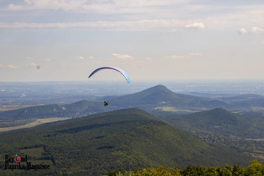 A paraglider drifts silently above the Pilis peaks
